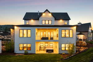 Rear view of property with a balcony, a patio, a yard, and a hot tub