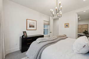 Bedroom with light carpet, a chandelier, baseboards, and recessed lighting