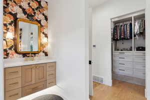 Bathroom with wood finished floors, vanity, baseboards, and a walk in closet