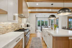 Kitchen with stainless steel stove, a sink, plenty of natural light, beam ceiling, and recessed lighting