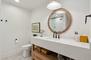 Bathroom with toilet, baseboards, a tile shower, recessed lighting, and vanity