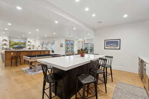 Kitchen featuring a large island, recessed lighting, light wood-style flooring, light countertops, and a breakfast bar