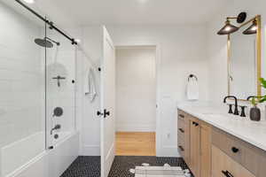 Bathroom featuring vanity, tile patterned floors, combined bath / shower with glass door, and baseboards