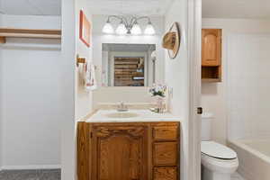 Full bath with toilet, vanity, and a textured ceiling