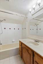 Full bathroom with tile patterned floors, lofted ceiling, bathing tub / shower combination, a textured ceiling, and vanity