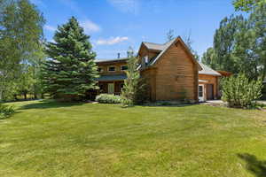 Rear view of house featuring a garage, a lawn, and log siding