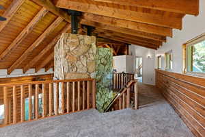 Hallway featuring an upstairs landing, wood ceiling, and carpet floors