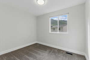 Spare room with dark colored carpet and baseboards