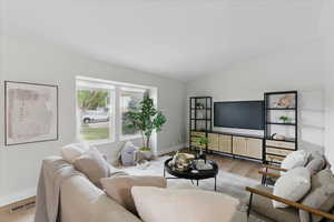 Living room featuring LVP floors, baseboards, and lofted ceiling