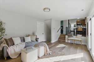 Living room featuring light wood-style floors, stairs, and baseboards