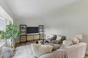 Living area featuring LVP floors, vaulted ceiling, and baseboards