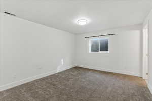 Unfurnished room with dark carpet and baseboards
