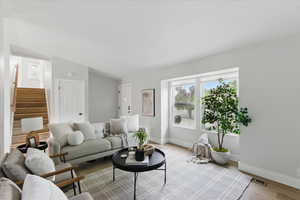 Living area featuring baseboards, LVP floors, stairway, and lofted ceiling