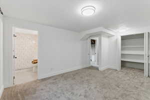 Unfurnished bedroom with carpet flooring, connected bathroom, baseboards, and a closet