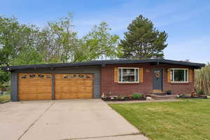View of front facade with driveway, a garage, a front lawn, and brick siding