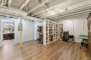 Below grade area with wood finished floors, electric panel, baseboards, and an office area