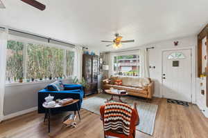 Living area with a ceiling fan, wood finished floors, and baseboards