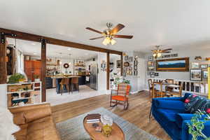 Living area featuring a ceiling fan, light wood-style flooring, and baseboards