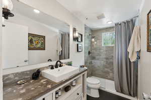 Full bathroom with tiled shower, toilet, and vanity