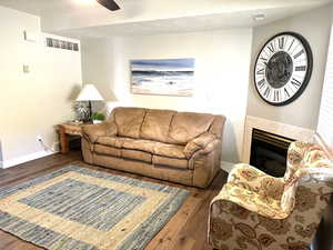 Living room featuring wood finished floors, baseboards, a tile fireplace, and ceiling fan