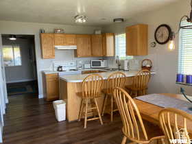 Kitchen featuring white microwave, light countertops, dark wood-style floors, and under cabinet range hood