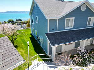 View of side of home featuring roof with shingles and a water and mountain view