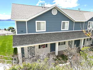 Rear view of house with roof with shingles and a lawn