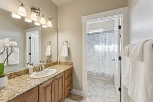 Full bathroom with vanity, shower / tub combo with curtain, and baseboards