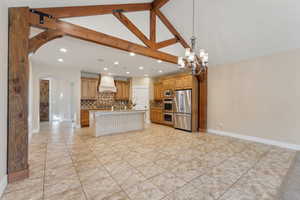 Kitchen with custom exhaust hood, stainless steel appliances, arched walkways, backsplash, and recessed lighting