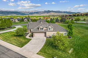 View of front of house featuring stone siding, a mountain view, concrete driveway, and a residential view