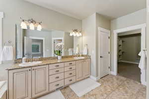Full bath featuring double vanity, tile patterned flooring, and a walk in closet