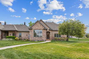 View of front of property with stucco siding, stone siding, and a front yard
