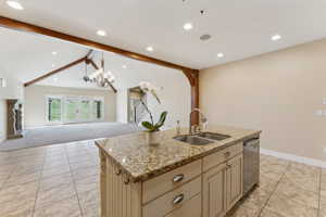 Kitchen with a sink, cream cabinets, dishwasher, open floor plan, and baseboards