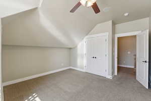Additional living space with vaulted ceiling, carpet flooring, a ceiling fan, and baseboards