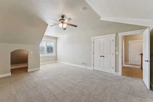 Additional living space with lofted ceiling, a ceiling fan, carpet floors, baseboards, and arched walkways