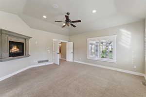 Unfurnished bedroom featuring vaulted ceiling, carpet flooring, a high end fireplace, baseboards, and recessed lighting