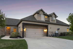 View of front of house featuring stone siding, stucco siding, and concrete driveway
