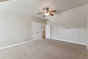 Additional living space with a ceiling fan, carpet, baseboards, and vaulted ceiling