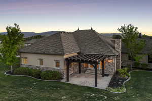 Rear view of house with a pergola, stucco siding, stone siding, a yard, and a patio area