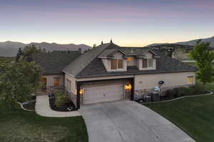 View of front of house featuring stucco siding, stone siding, driveway, a front yard, and central AC unit