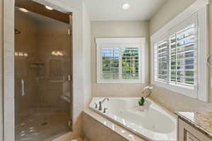 Bathroom with a stall shower, a jetted tub, plenty of natural light, vanity, and recessed lighting