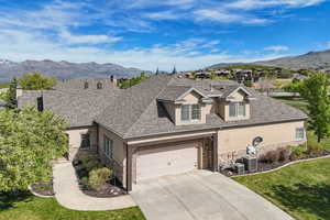 View of front of home with stucco siding, stone siding, concrete driveway, and a mountain view