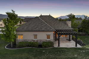 View of side of property with stone siding, a pergola, stucco siding, and a lawn