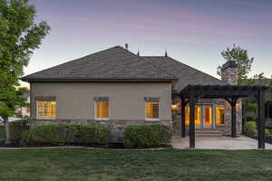 Rear view of house with stone siding, a yard, stucco siding, and a shingled roof