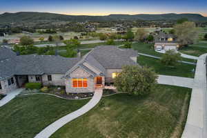 View of front of property with stone siding, a mountain view, and a front lawn