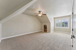 Bonus room featuring light colored carpet, a ceiling fan, vaulted ceiling, and baseboards