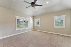 Spare room featuring baseboards, light colored carpet, a ceiling fan, and lofted ceiling