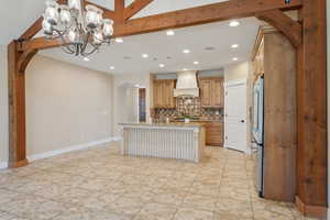 Kitchen featuring custom range hood, arched walkways, recessed lighting, decorative backsplash, and light stone counters