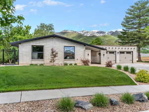 View of front of home with driveway, a mountain view, an attached garage, and brick siding