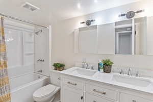 Bathroom featuring shower / tub combo, toilet, and double vanity